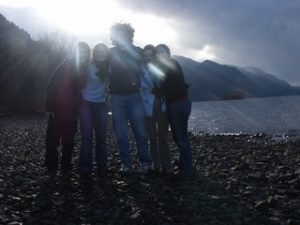 people on a pebbled beach backlit by sun