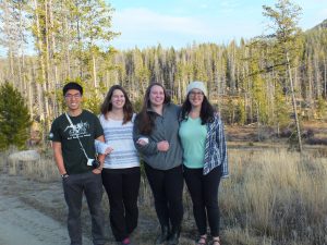 four people standing, arms linked