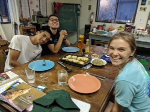 three people smiling, sitting at a dinner table