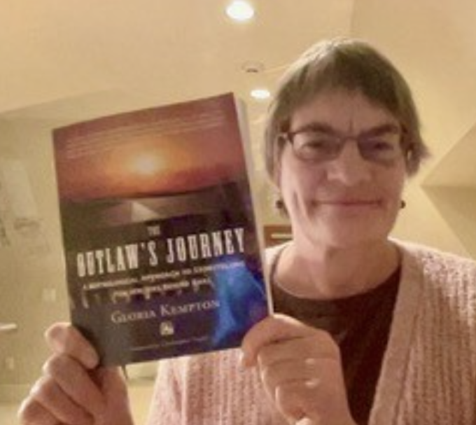 Author holding up a book entitled "The Outlaw's Journey"